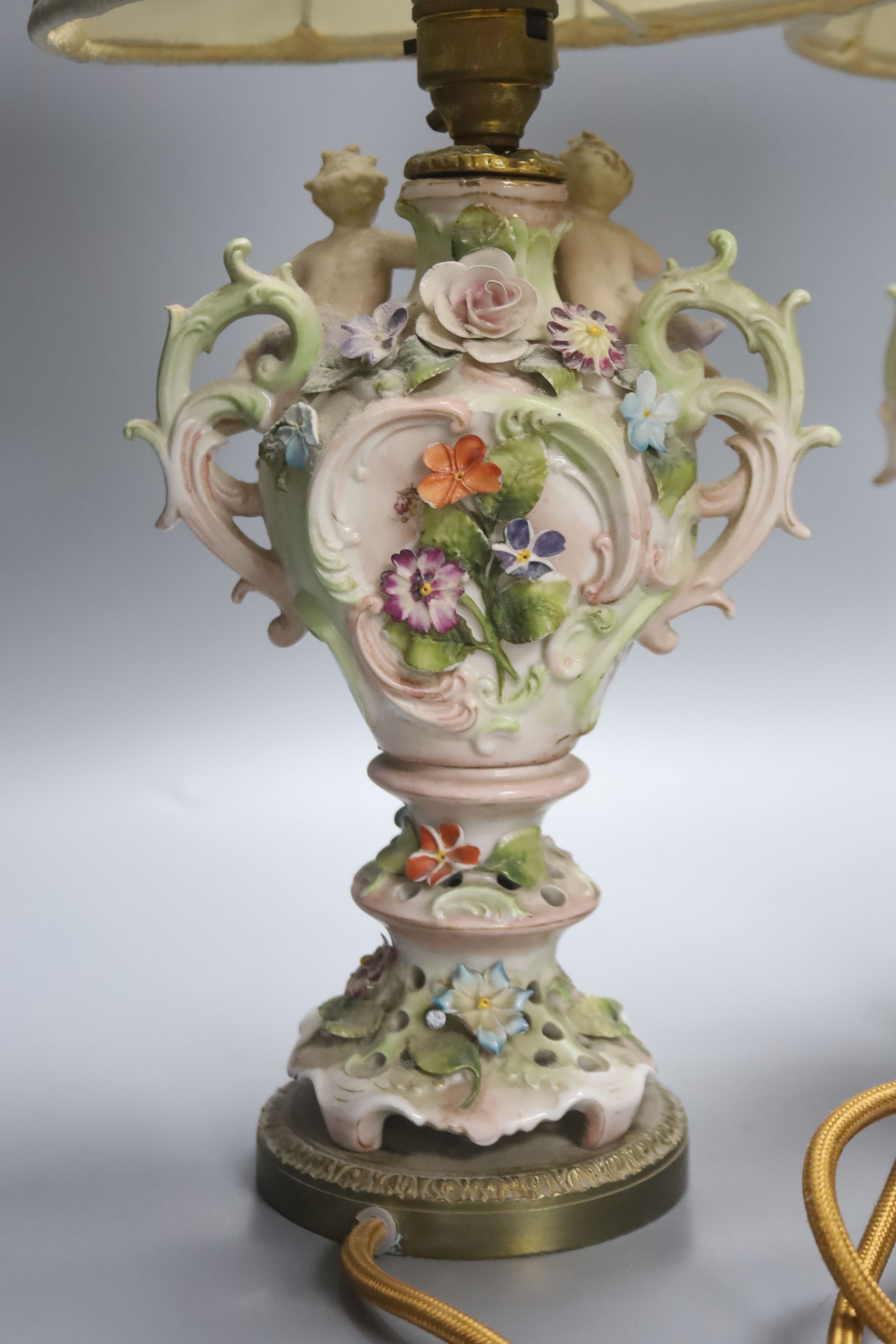 A pair of German porcelain flower encrusted lamps, height 24cm